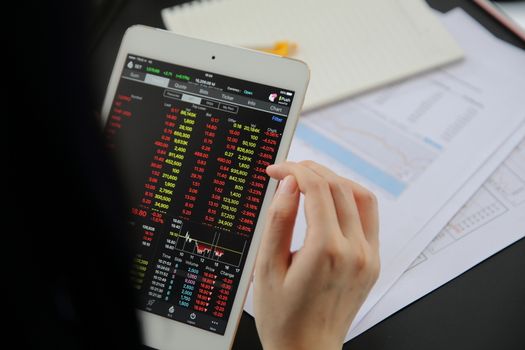 Woman hand Trading online on tablet with business paper and coffee