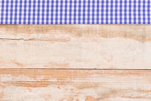 Rustic wooden table surface with blue checkered cloth, top view
