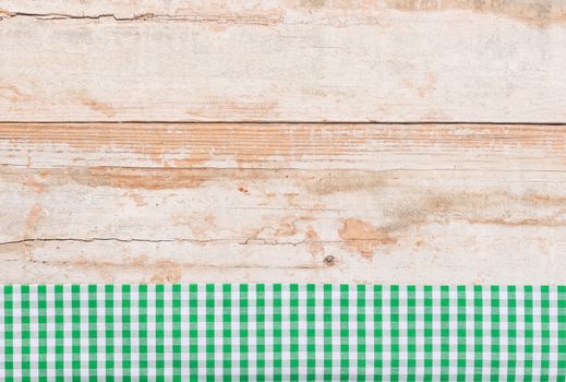 Rustic wooden table surface with green checkered cloth, top view