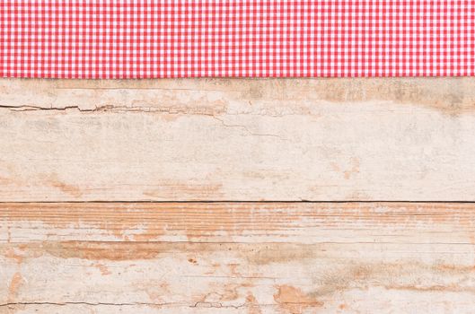 Rustic wooden table surface with red checkered cloth, top view