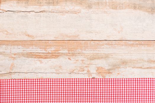 Rustic wooden table surface with red checkered cloth, top view