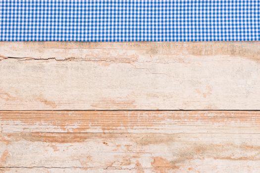 Rustic wooden table surface with blue checkered cloth, top view