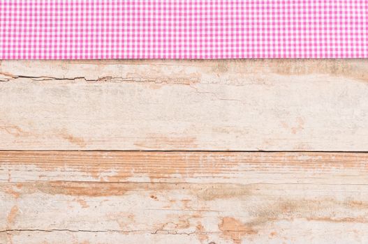 Rustic wooden table surface with pink checkered cloth, top view
