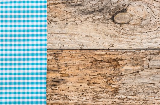 Blue checked tablecloth on rustic wooden table background, top view