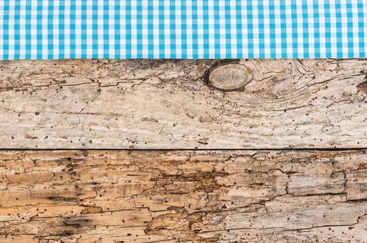 Rustic wooden table surface with blue checkered cloth, top view