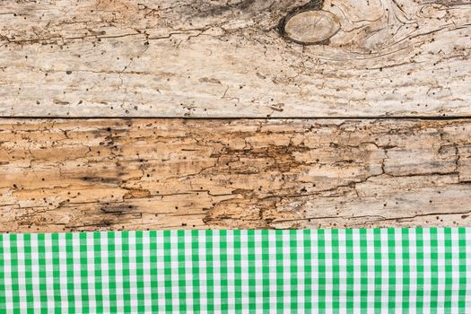 Rustic wooden table surface with green checkered cloth, top view