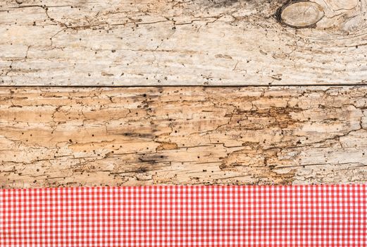 Rustic wooden table surface with red checkered cloth, top view
