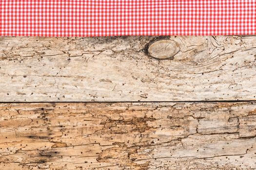 Rustic wooden table surface with red checkered cloth, top view