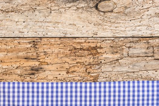Rustic wooden table surface with blue checkered cloth, top view