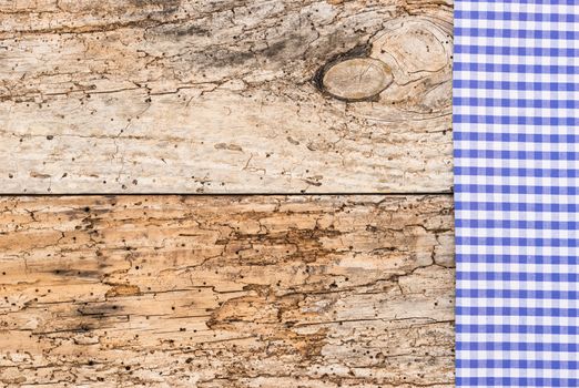 Blue checked tablecloth on rustic wooden table background, top view