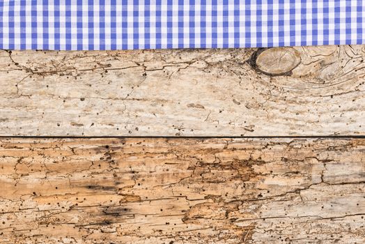 Rustic wooden table surface with blue checkered cloth, top view