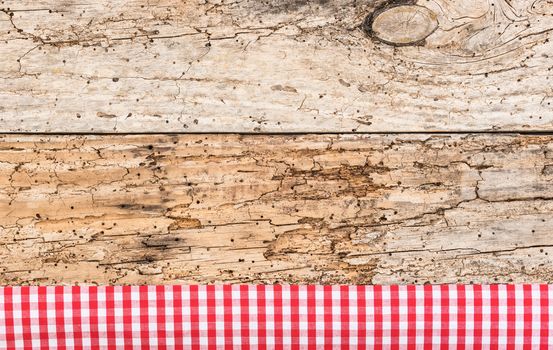 Rustic wooden table surface with red checkered cloth, top view
