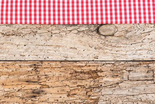 Rustic wooden table surface with red checkered cloth, top view