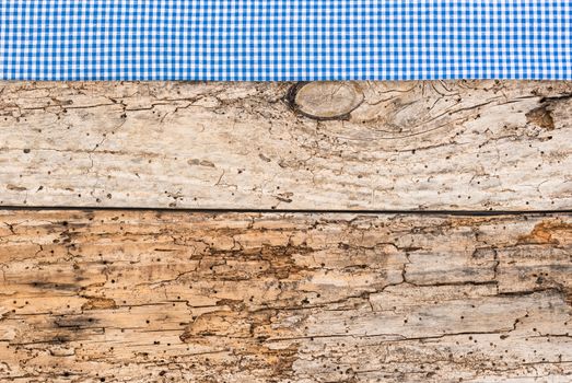 Rustic wooden table surface with blue checkered cloth, top view