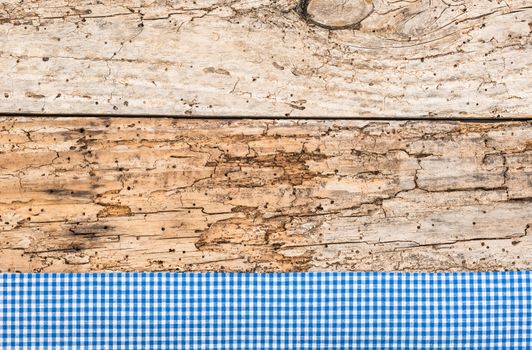 Rustic wooden table surface with blue checkered cloth, top view