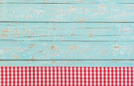 Red checked tablecloth on blue wooden kitchen table background