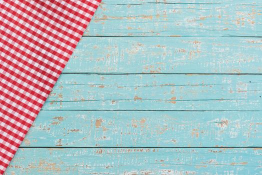 Red checkered tablecloth on rustic blue wooden table background