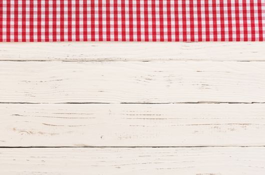 Red checkered tablecloth on rustic white wooden table background
