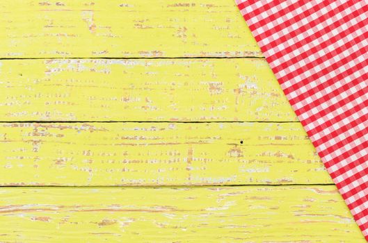 Rustic yellow kitchen table background with red checked tablecloth
