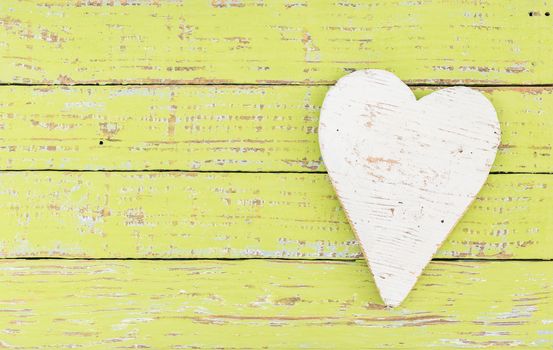 White wooden heart on green wood background with copy space
