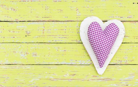 Fabric purple heart on green wooden background with copy space