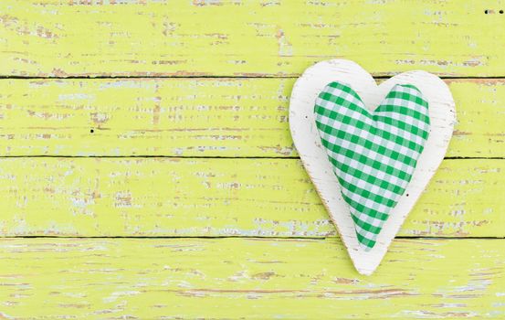 Green fabric heart on wooden background with copy space