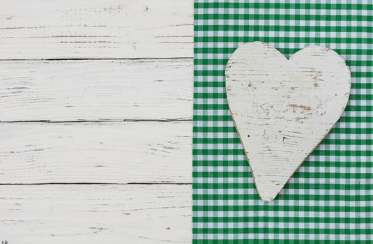 White wooden heart on green textile border and background with copy space