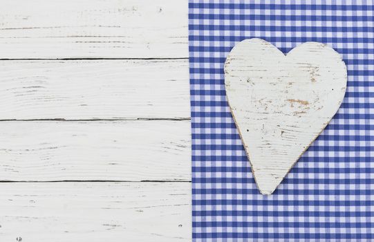 White wooden heart on blue textile border and wood with copy space