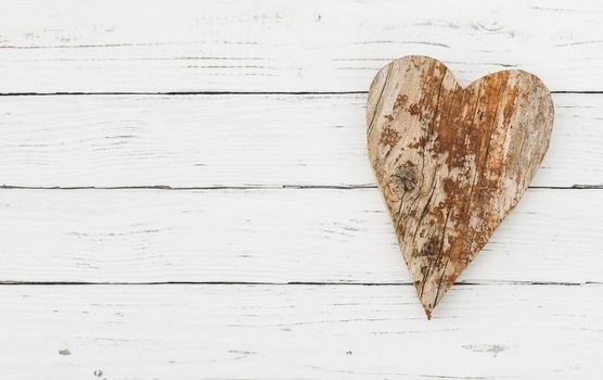 Brown wooden heart shape on white wood background with copy space
