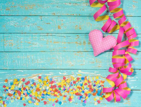Streamers, confetti and heart decoration on blue wood background for party or birthday celebration
