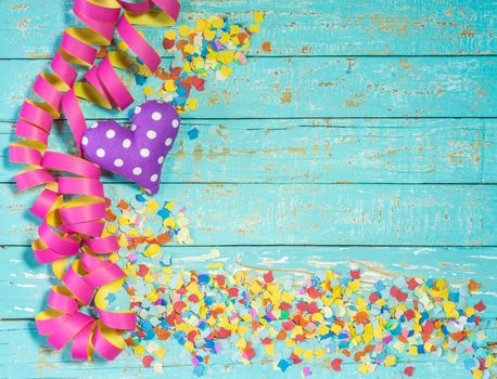 Streamers, confetti and heart decoration on blue wood background for party or birthday celebration