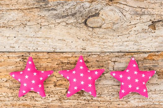 Pink fabric stars decor on old wooden background with copy space