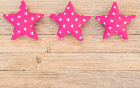 Frame of pink fabric stars on wooden background with copy space