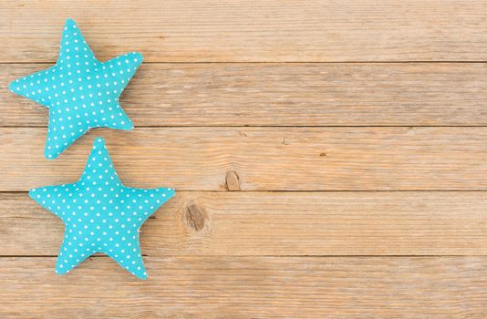 Blue fabric stars on wooden background with copy space