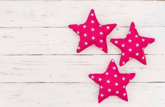 Decoration with three pink stars on white wood with copy space