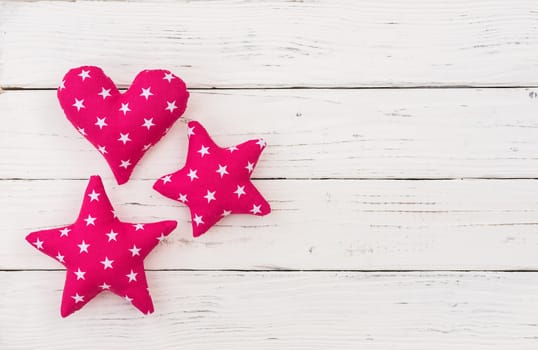 Pink fabric stars and heart decoration on white wooden background with copy space