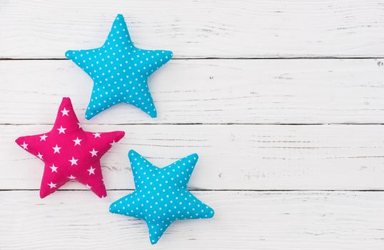 Three fabric stars on white wooden background with copy space