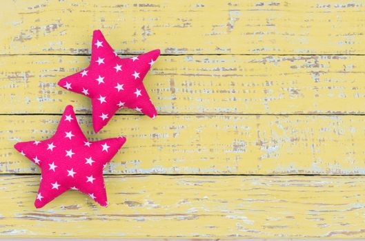 Fabric stars decor on yellow wooden background with copy space