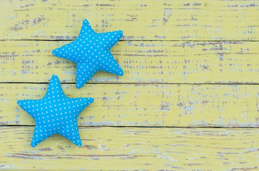 Blue fabric stars on green wooden background with copy space