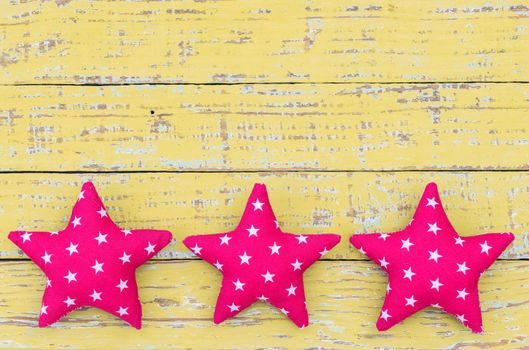 Fabric stars decor on yellow wooden background with copy space