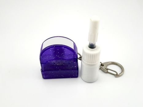 Liquid black refill ink placed in small white plastic bottle and Small purple plastic glitters stamp with metal key ring use to stamp on paper