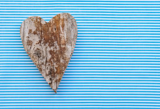 Handmade wooden heart shape on light blue background with copy space