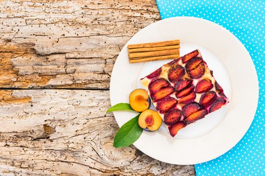Piece of plume cake on plate on rustic wooden table background, top view