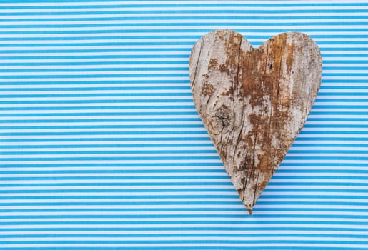 Handmade wooden heart shape on blue fabric background with copy space