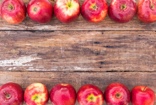 Apples background with juicy red fruits on wooden table with copy space