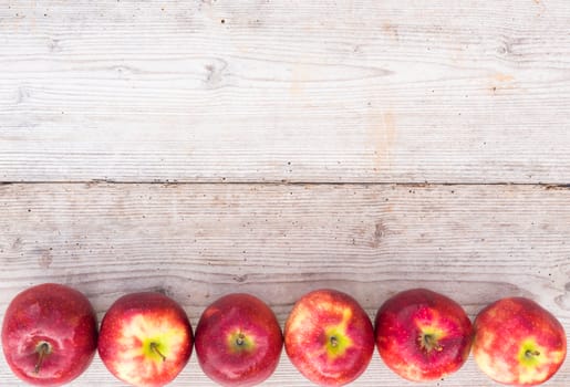 Apples background with juicy red fruits on wood, top view with copy space