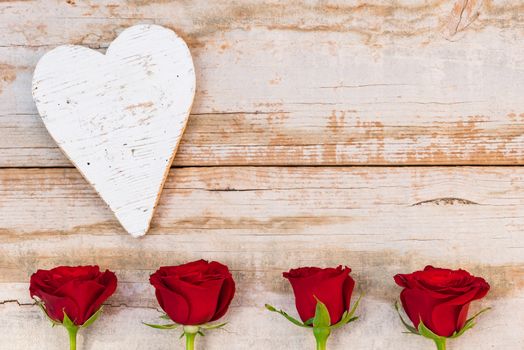 Valentine background with red roses and heart on rustic wood with copy space