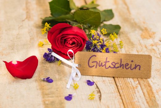 Bunch of red rose flower and tag with german word, Gutschein, means voucher or coupon