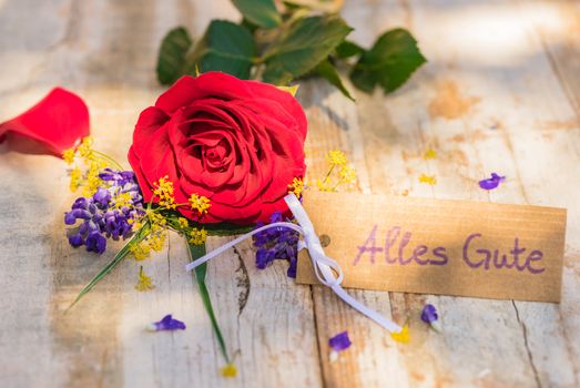 Red rose flower bunch and tag with german text, Alles Gute, means all the best