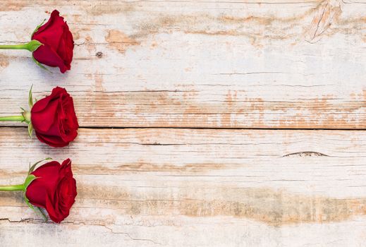 Romantic red roses background on rustic wood with copy space